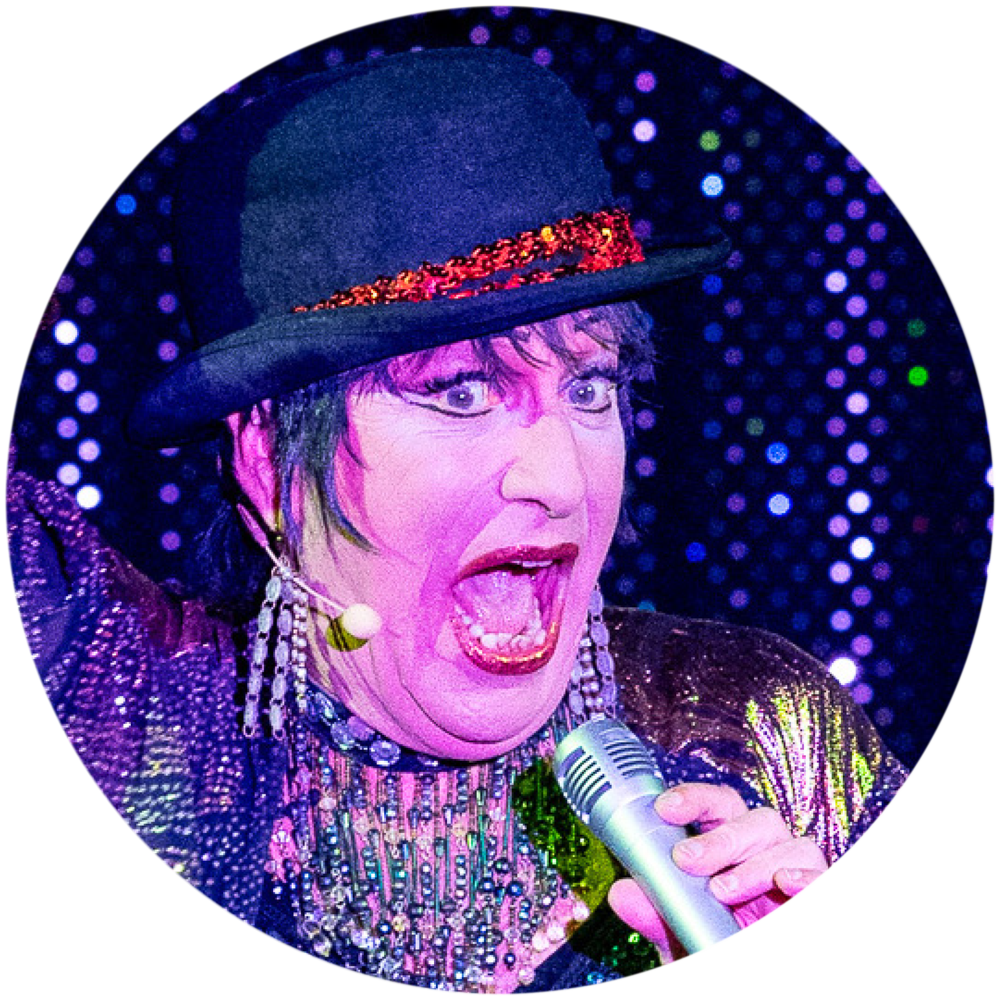 Eine Szene aus dem Musik-Kabarett Stars on Stage zeigt einen Mann, der Liza Minnelli in ihrer Rolle als Sally Bowles aus Cabaret mimt. Mit starken, markanten Gesichtszügen und einer intensiven Mimik singt er das Lied Welcome to Cabaret. Er trägt das charakteristische Outfit von Sally Bowles, inklusive einem glitzernden Kostüm und einer auffälligen Frisur, und bringt die Energie und den Charme von Liza Minnelli perfekt auf die Bühne.